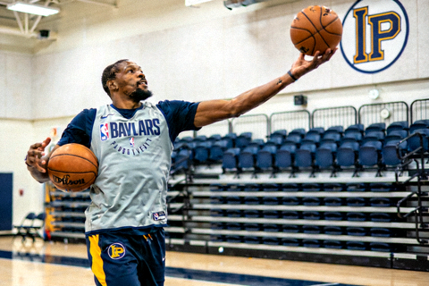 NBA球员在训练馆进行投篮训练的场景照片，背景是空荡的观众席
